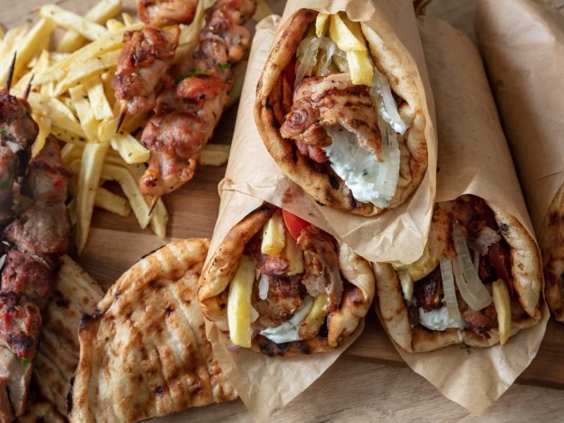 Greek street food, gyro sliced meat pita bread wrap and souvlaki skewer, overhead