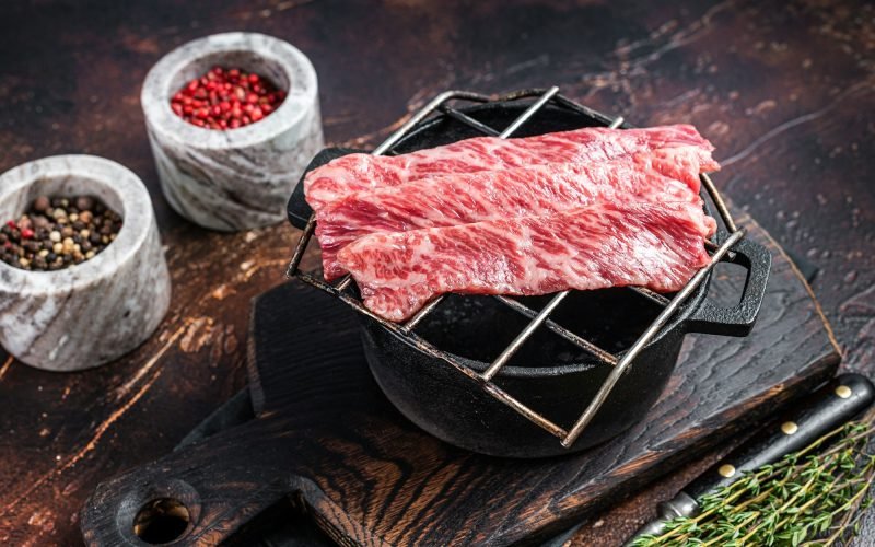 Premium raw sliced wagyu beef A5 steaks on a grill for yakiniku. Japanese foods.
