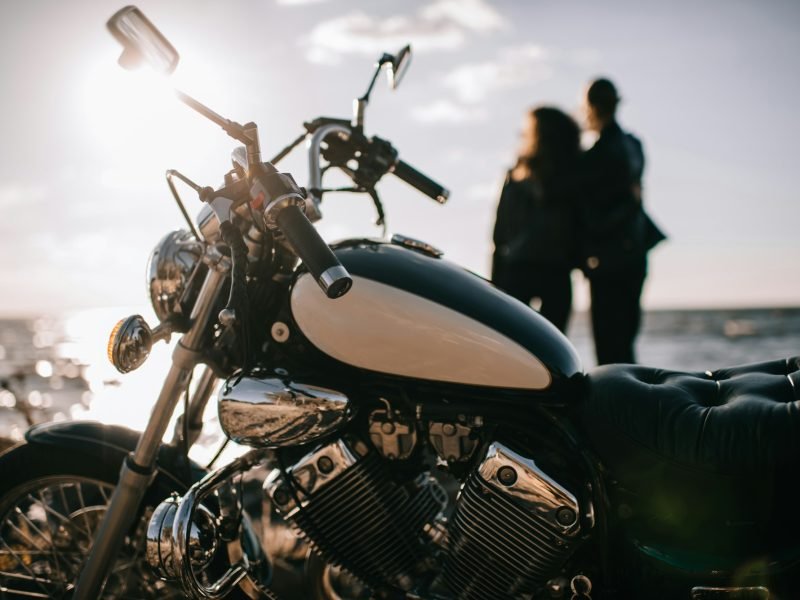 selective focus of classical chopper motorbike and couple looking at sea on background